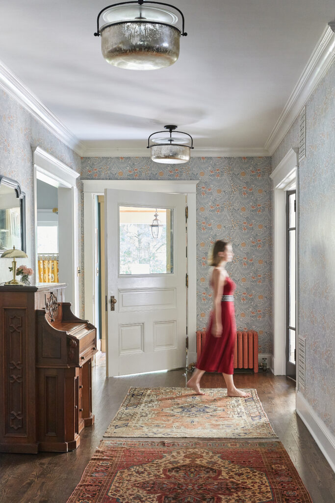 Interior designer Meghan Jay walking through the restored entryway of her family's 1890 Queen Anne Victorian home in Chicago.